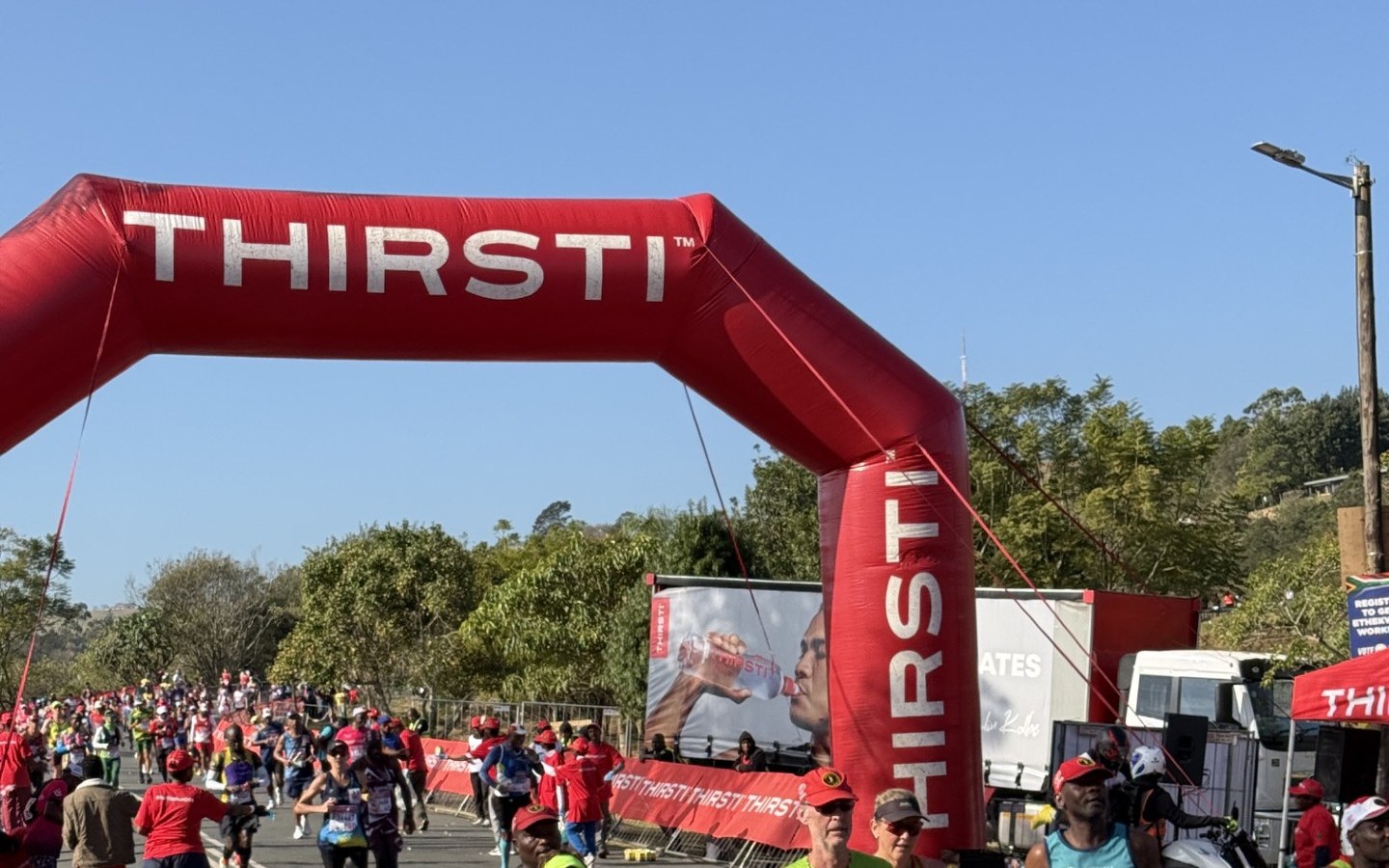 Runners passing under the THIRSTI arch at halfway